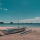 A traditional outrigger boat on the sand at El Nido, Palawan, with small islands on the horizon