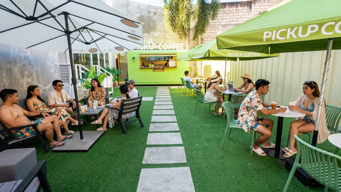 A group of travelers enjoys coffee at PickUp Coffee in Dumaguete, Philippines while sitting outside under sunshade umbrellas.