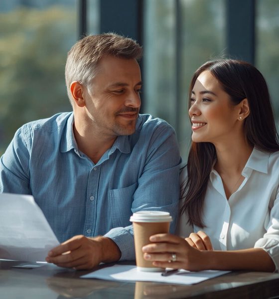 AI-generated image of a smiling man and woman at a café table, looking at each other while he holds a document and she holds a coffee cup