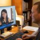 A man looking at a video messenger screen on his computer.